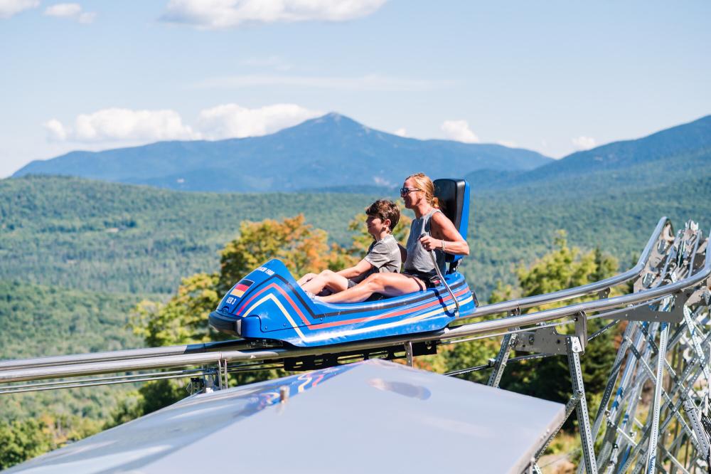 A woman and her sun ride a one-car coaster over mountains.