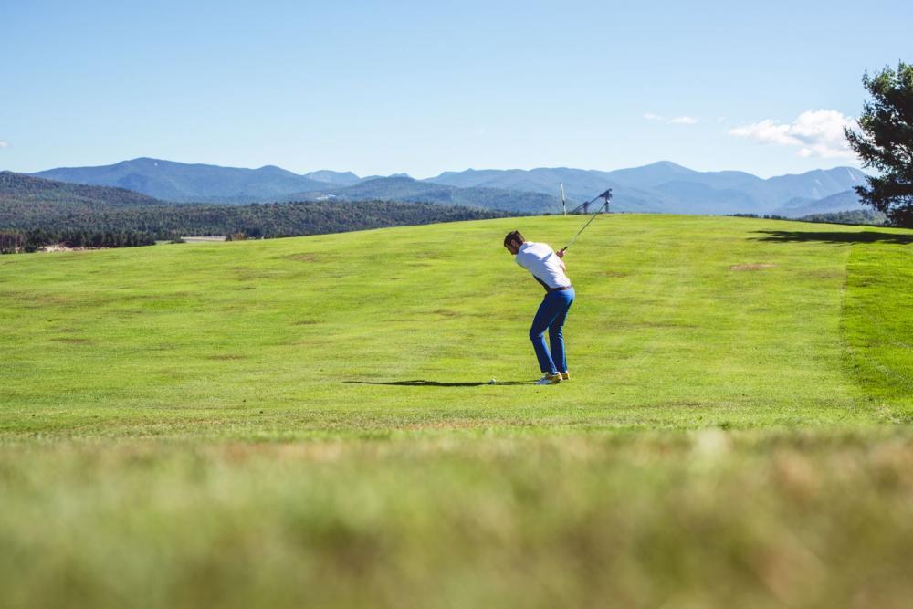 A male golfer swings on the fairway at a Lake Placid golf course.