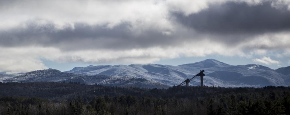 A view of the ski jumps in Lake Placid with snowy mountains behind them.