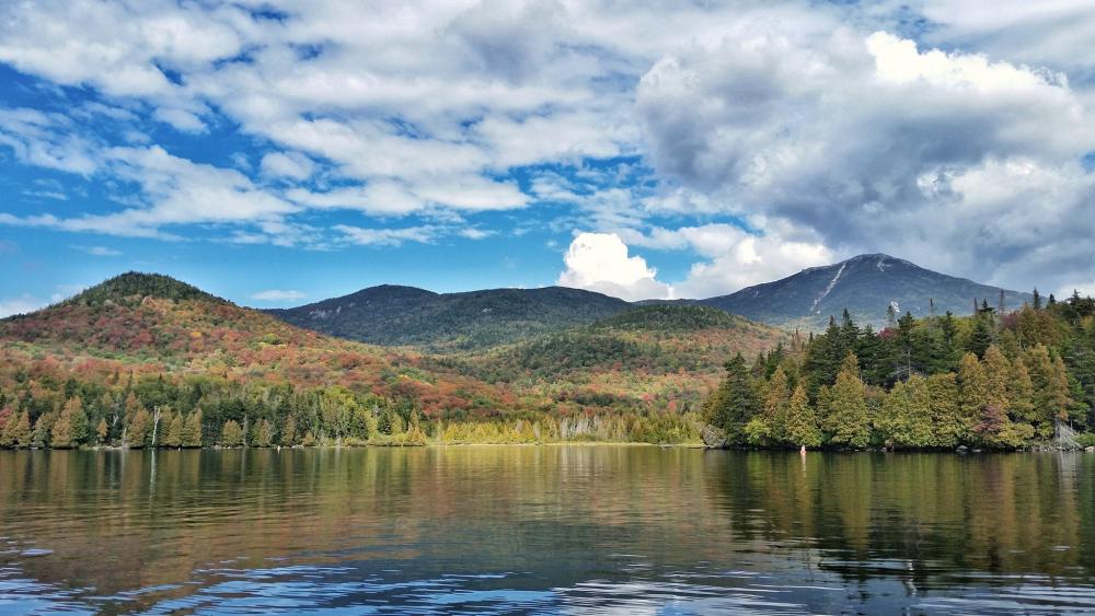 Calm waters and fall colors from a boat in Lake Placid. The trees are starting to turn red.