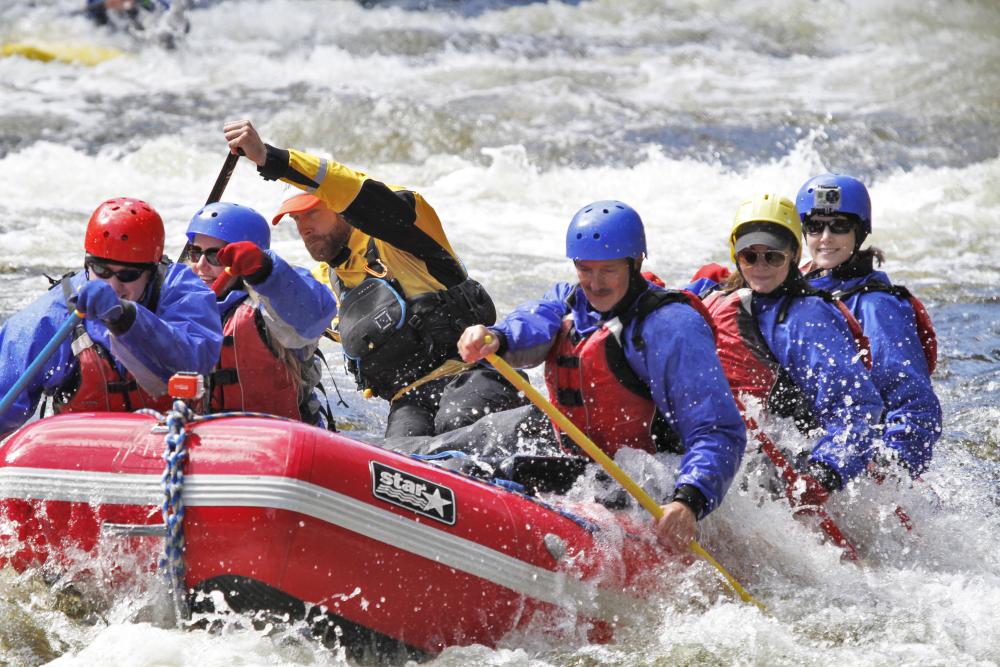 A group paddles through rapids on a group raft.