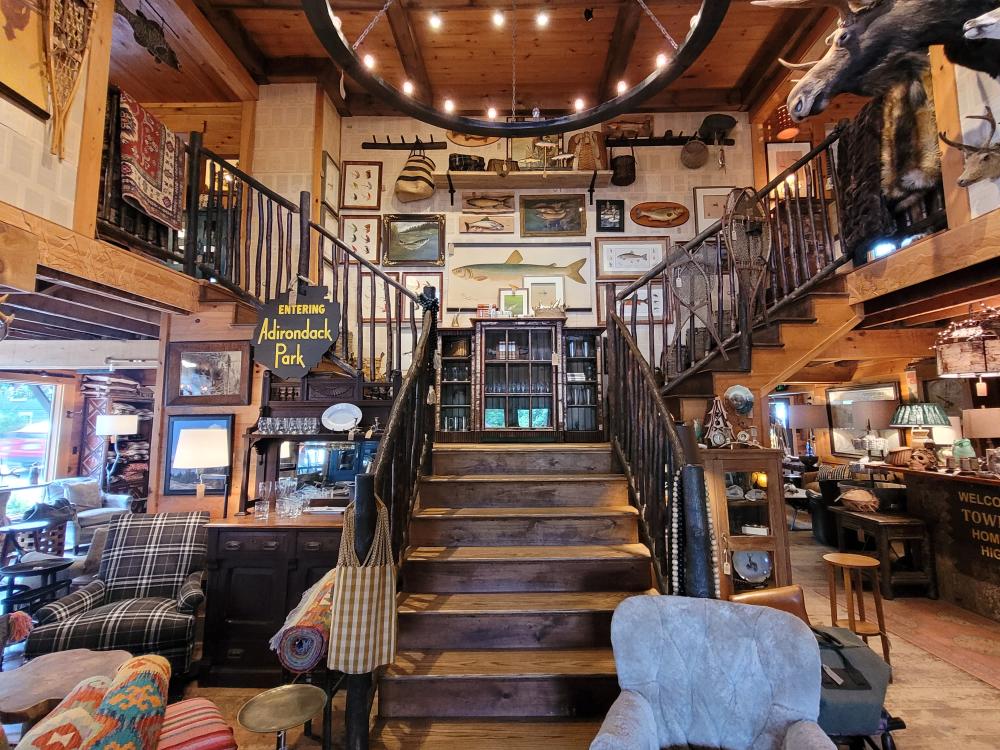 The interior of Dartbrook Rustic Goods is steeped in Adirondack style. A grand staircase leads to the second floor with home decor items throughout the building.
