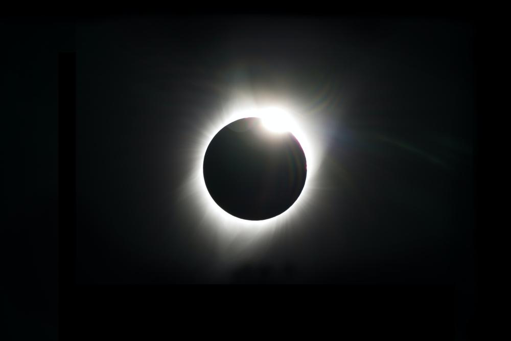 A black sky shows a total solar eclipse: a ring of white light surrounding a black disk, which is the moon
