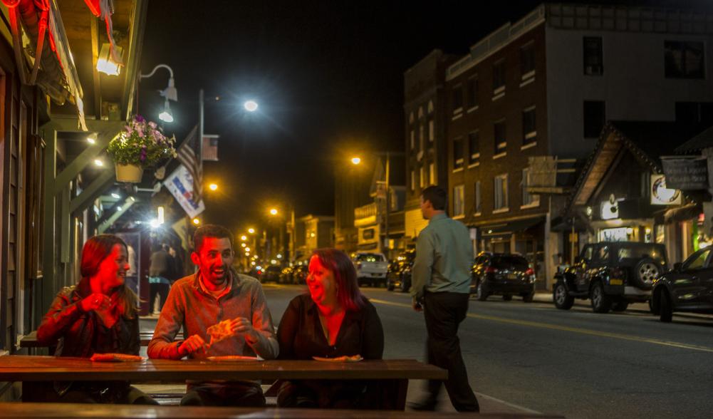 A couple people hanging out at night at a table on Main Street