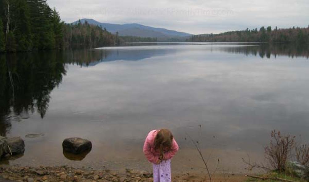 child explores shore of Franklin Falls Pond