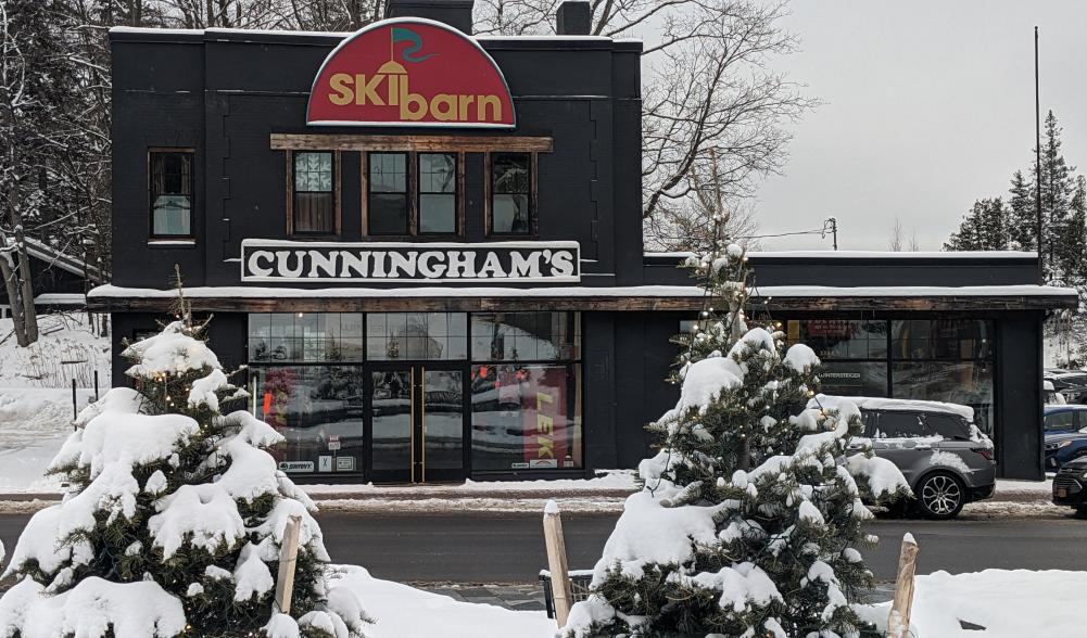 A ski shop is surrounded by snow-capped trees.