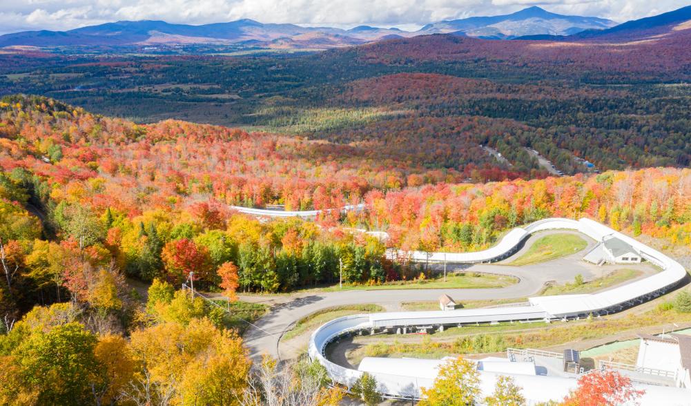 An aerial view of the bobsled track against a sea of colorful fall foliage.