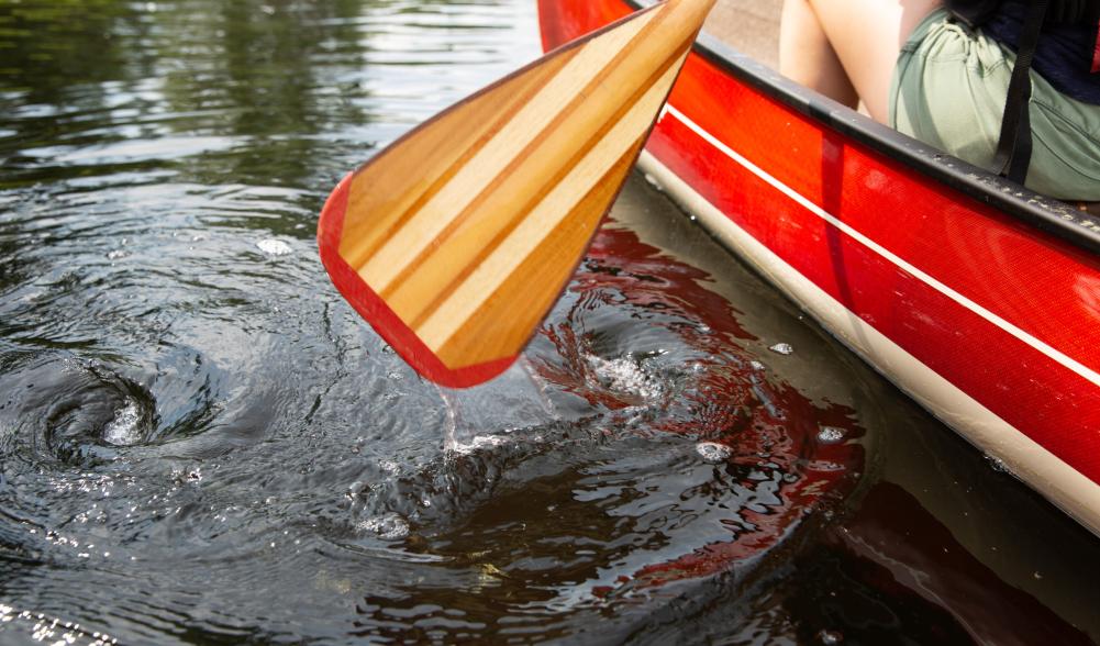 A red canoe and wooden paddle