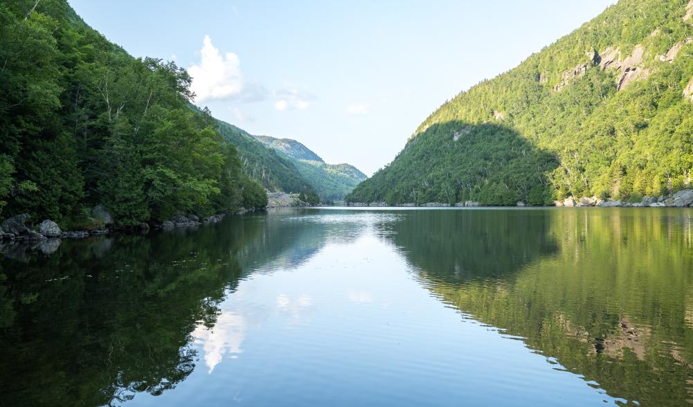 The peaceful waters of an Adirondack lake with dramatic cliffs on each side.