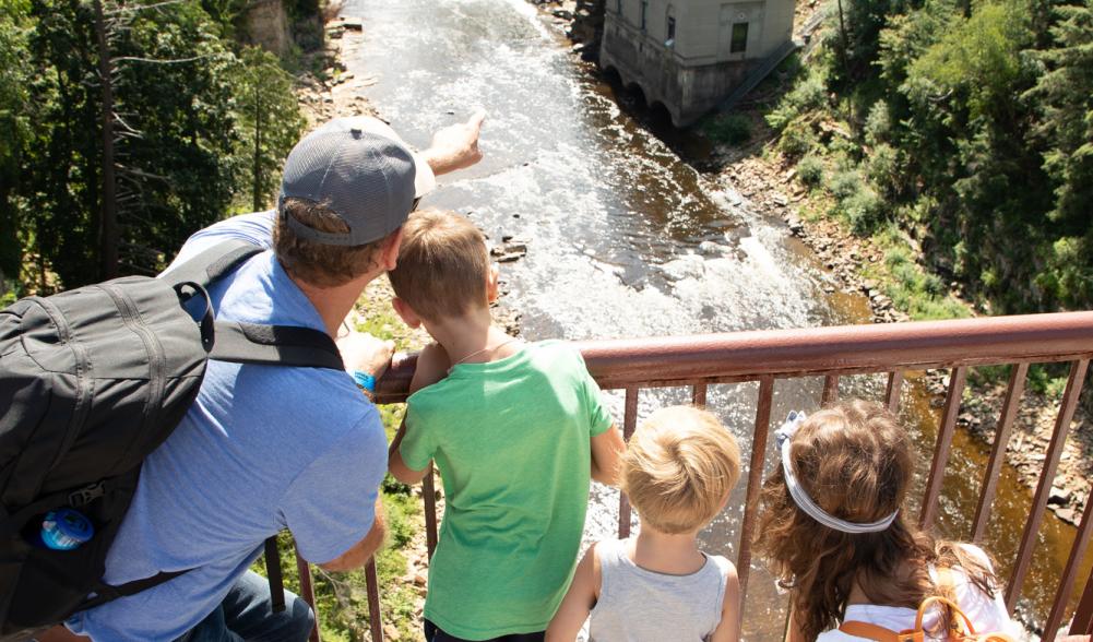 A man points to Ausable Chasm with his children.
