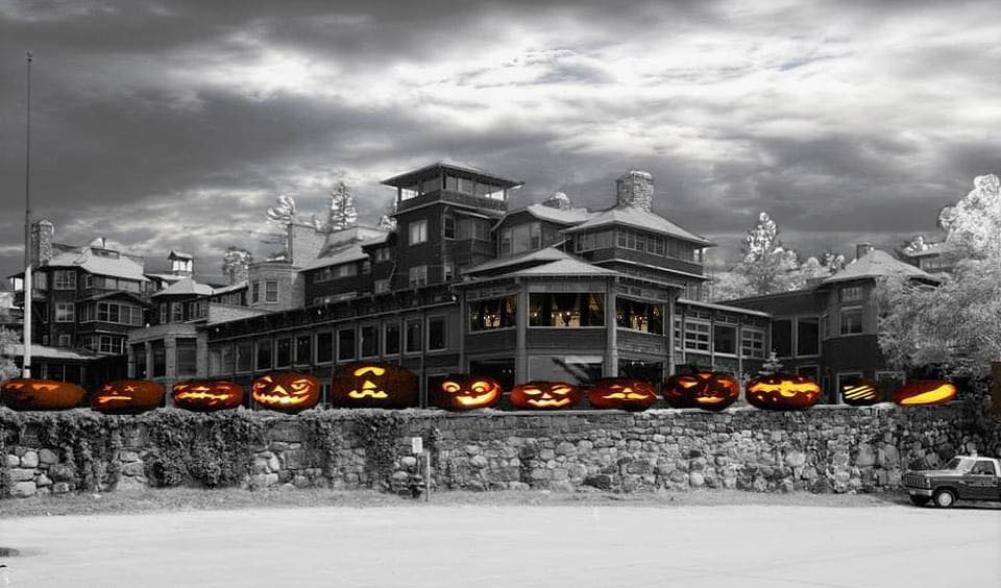 A black and white image of an old Adirondack hotel, photoshopped with spooky cartoon pumpkins