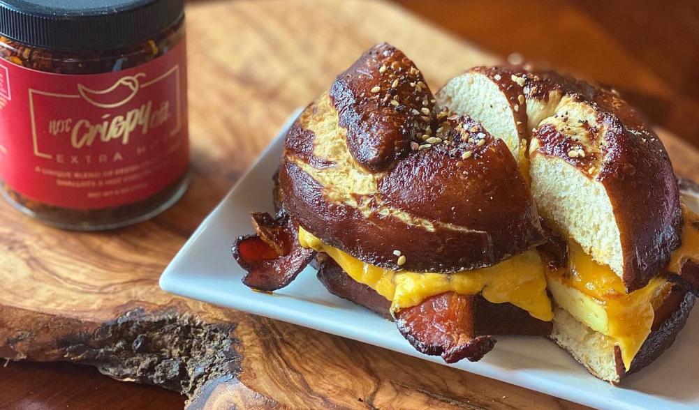 A bacon egg and cheese sandwich on a pretzel bun on a plate.