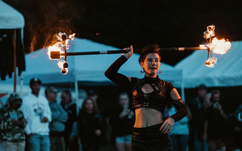 Smoke show fire dancer twirls double-ended fire baton