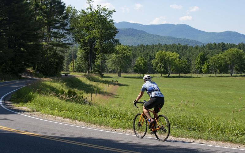 Cyclist on country road with mountain range in background