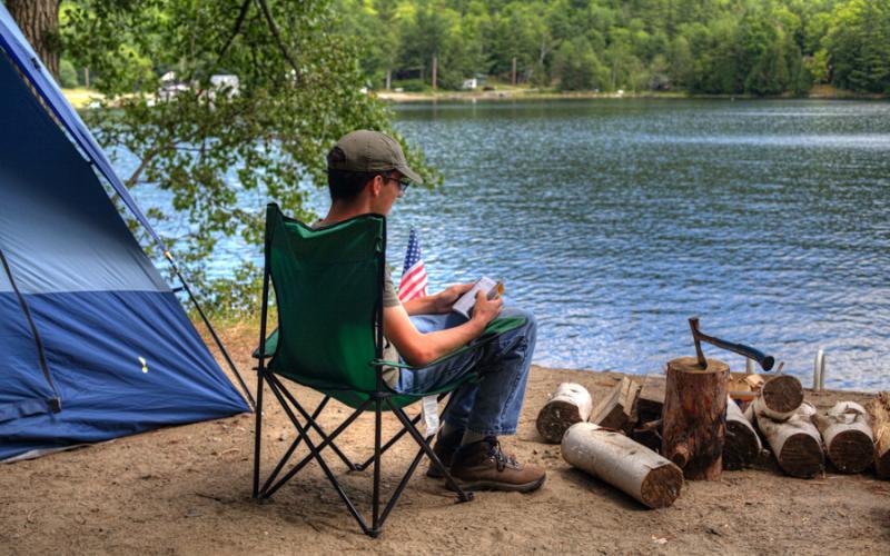 A person sitting in a camp chair by the water.