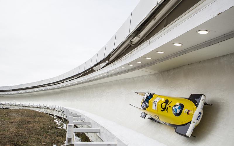 A team of two in a yellow German bobsled glides down the Lake Placid track