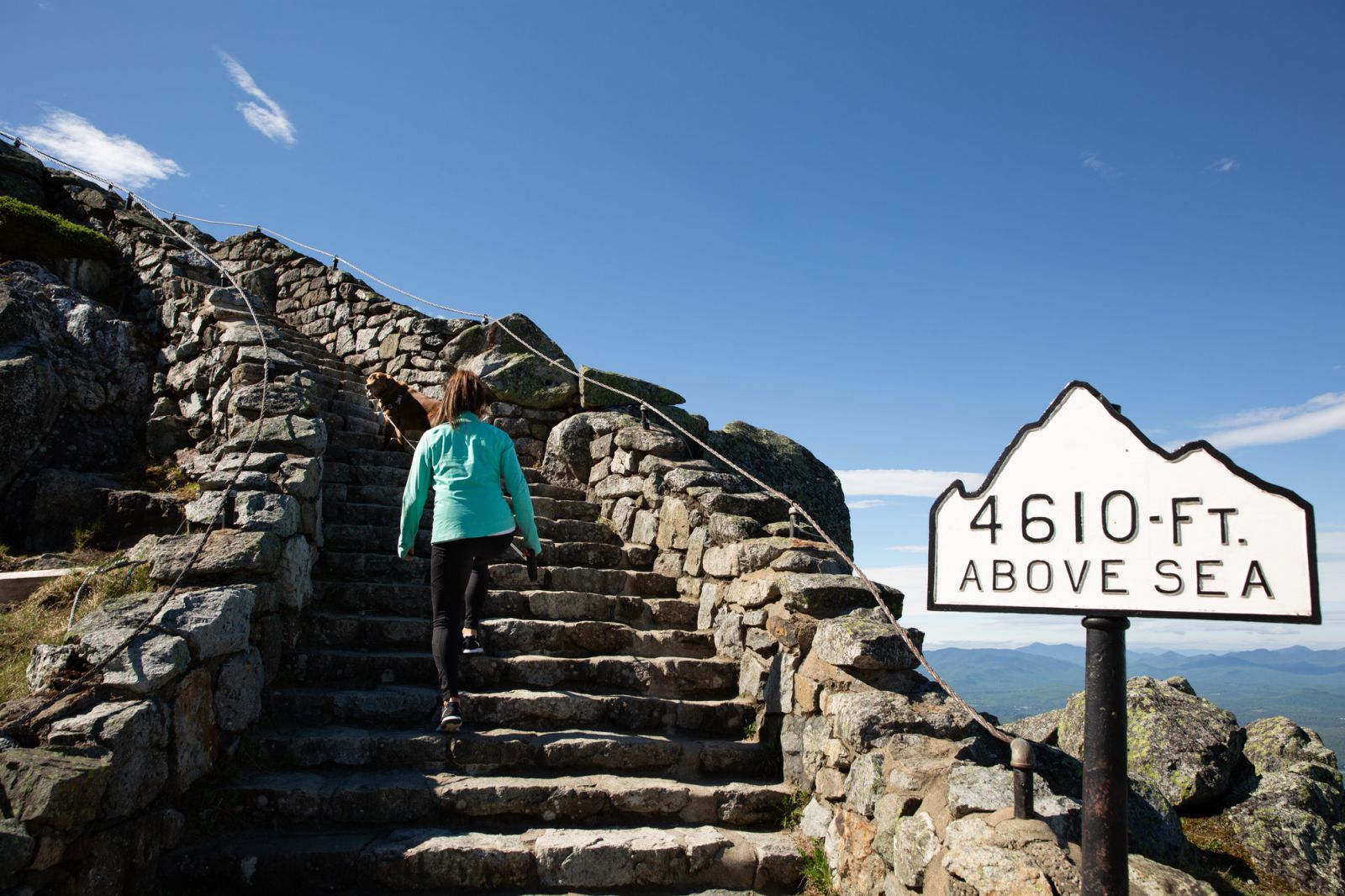 Visitors ascend the stairs towards Whiteface castle on the summit with mountains in the background.