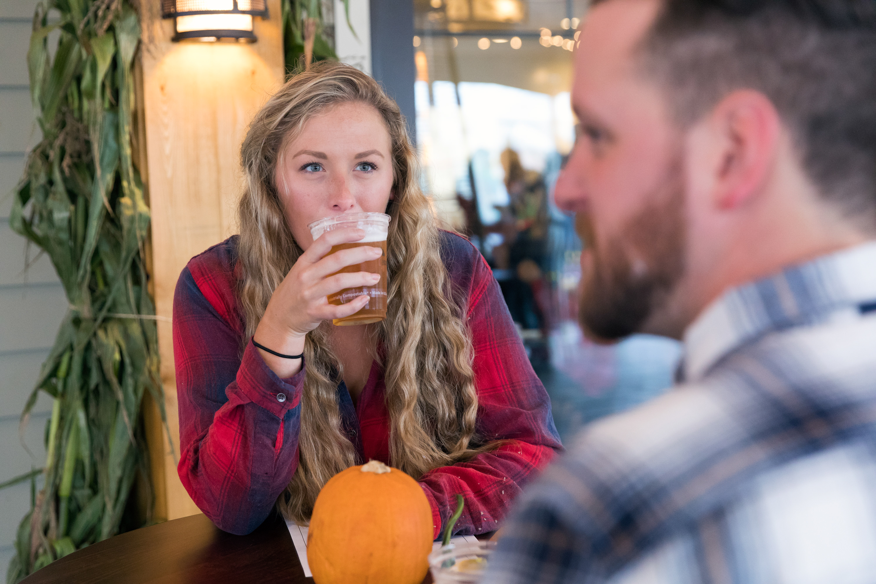A young woman drinking a beer in Lake Placid in the fall.