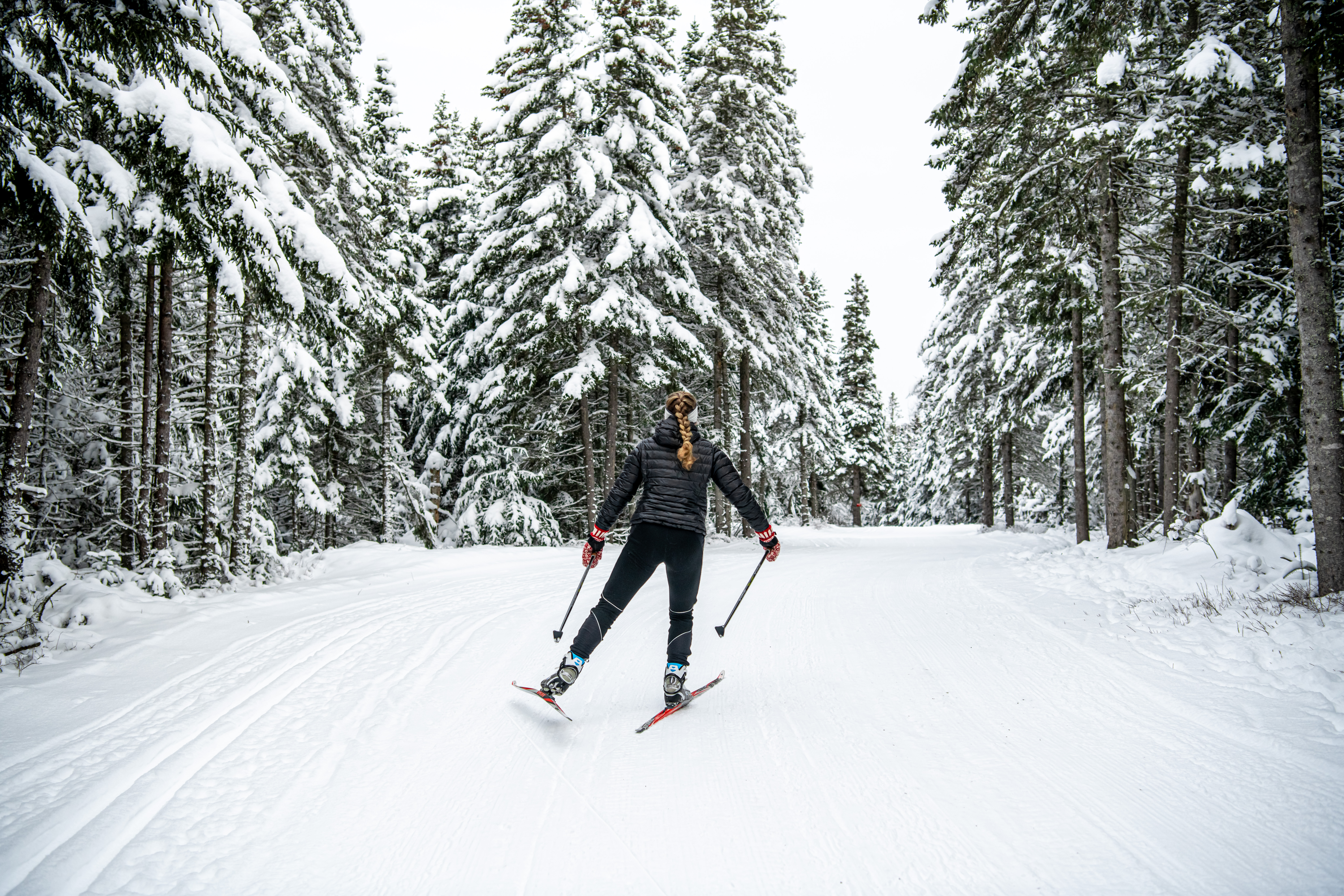 Woman cross-country skiing on snowy trail.