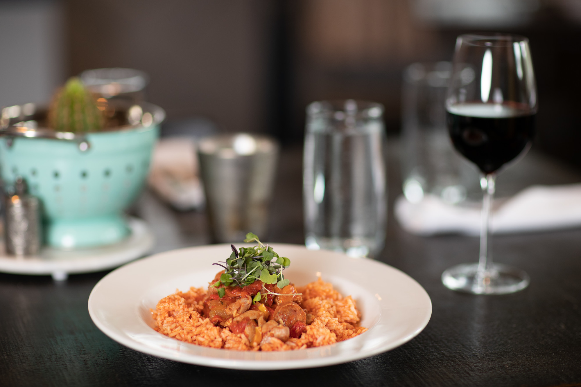 A plate of rice and jambalaya and glass of wine on a modern dining table.