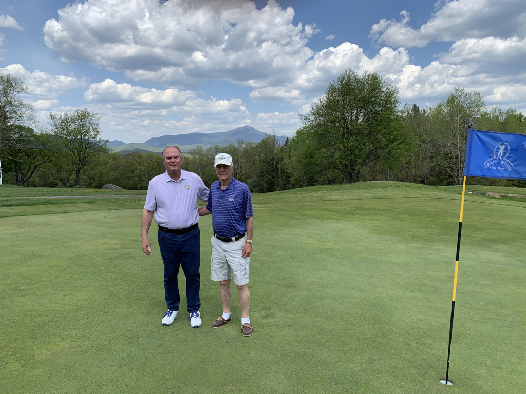 Craig Wood golf pro Jeff Estes and staff member Dick Strack pose on a green with Adirondacks in the background.
