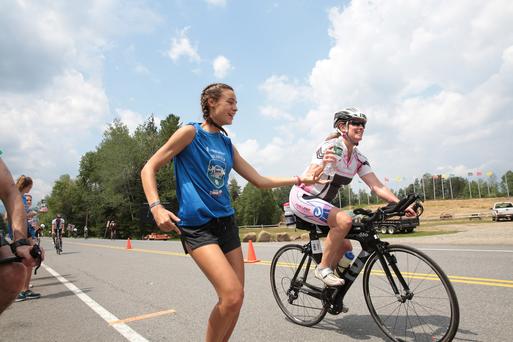 A volunteer hands off a bottle of water to a cyclist during the Ironman triathlon