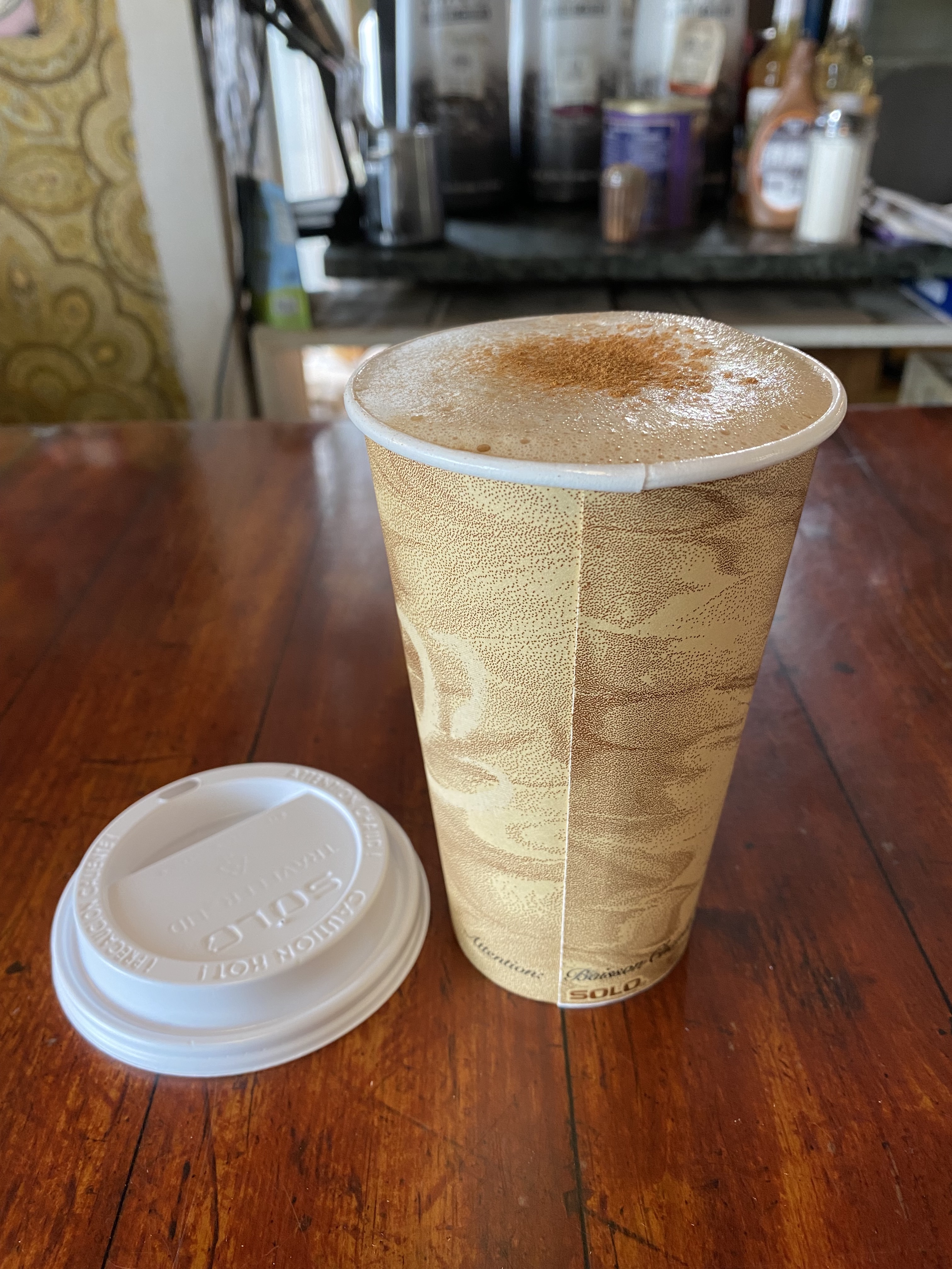 A foamy coffee drink on a wooden counter.