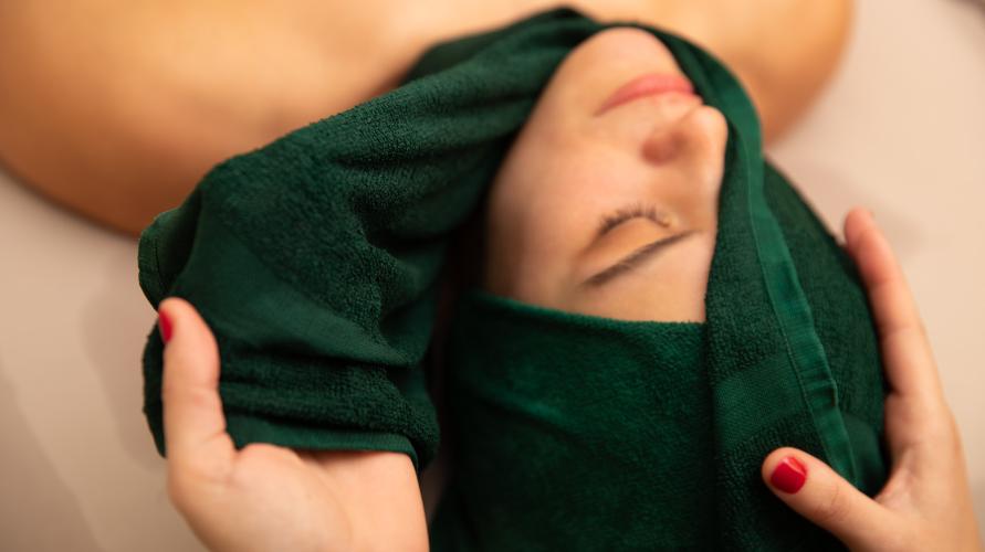 A woman has a hot towel placed on her head. 