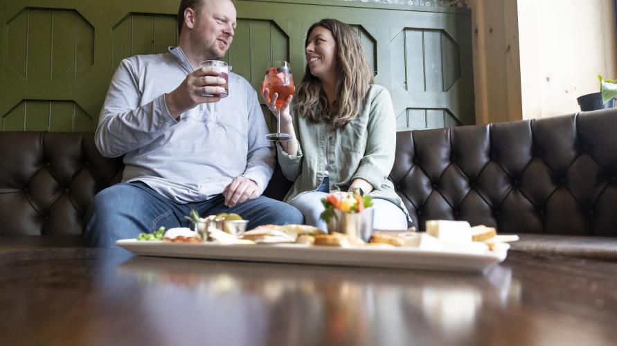 A man and woman toast with a charcuterie board