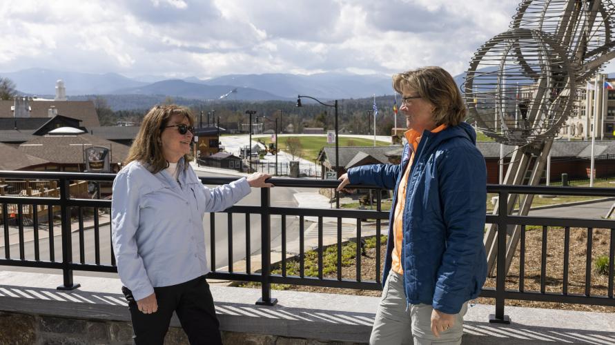 Two women stand on a balcony.