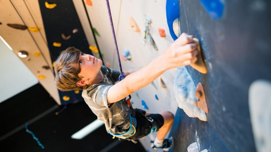 A teenager ascends a climbing wall