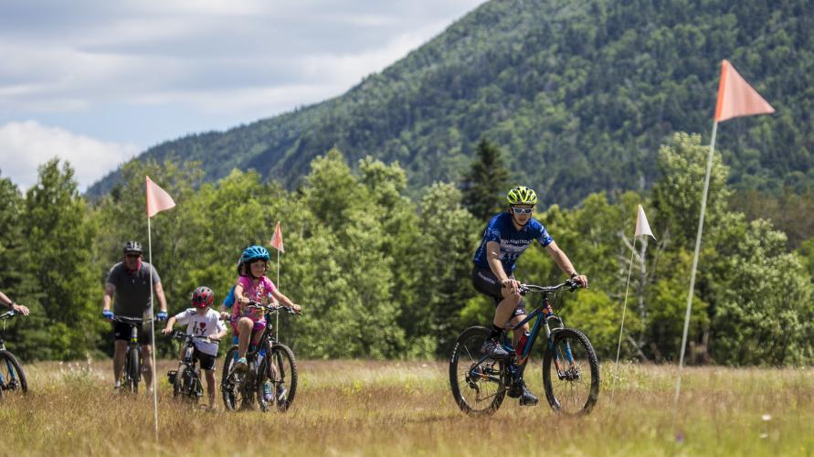 Adult and child mountain bikers on a flat trail in the Adirondacks.
