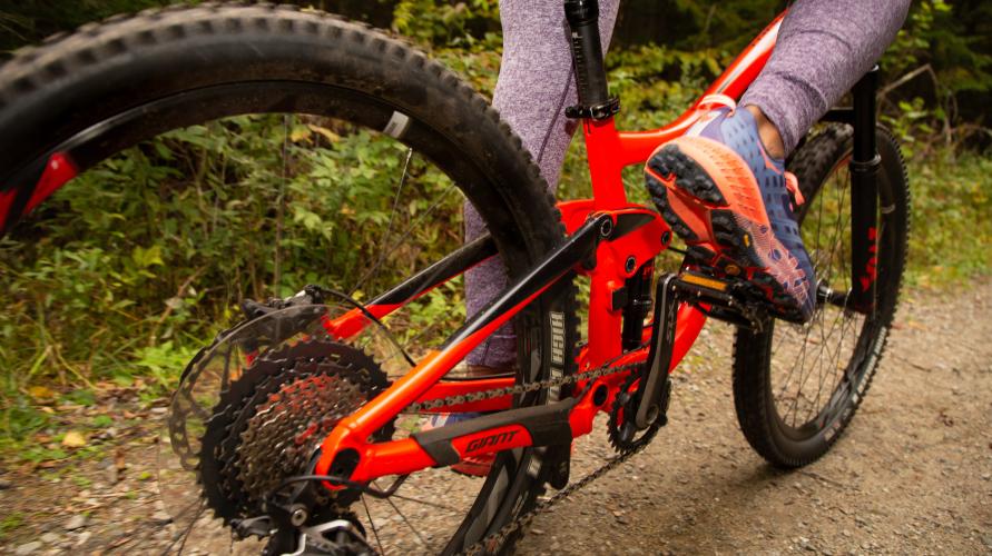 A close up of the back wheel of a red bike with someone pedaling forward.