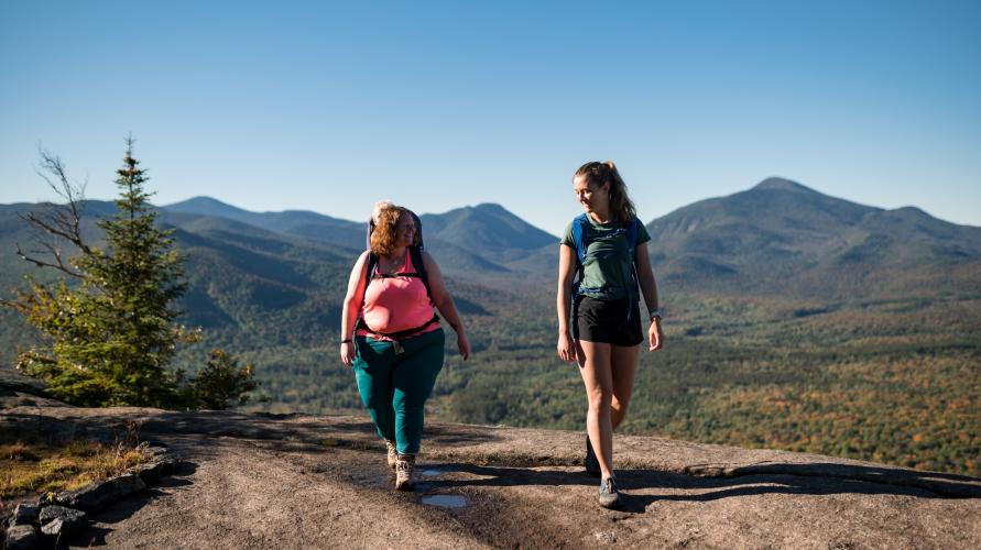 Two women hiking on a rocky mountain summit