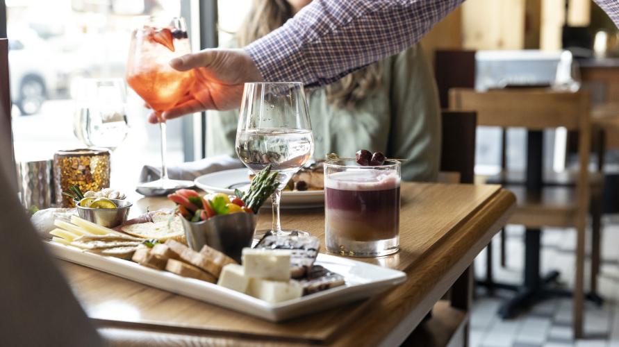 A couple dines on a charcouterie board and cocktails.