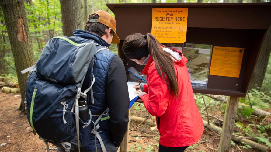 Two hikers sign in at an Adirondack trailhead