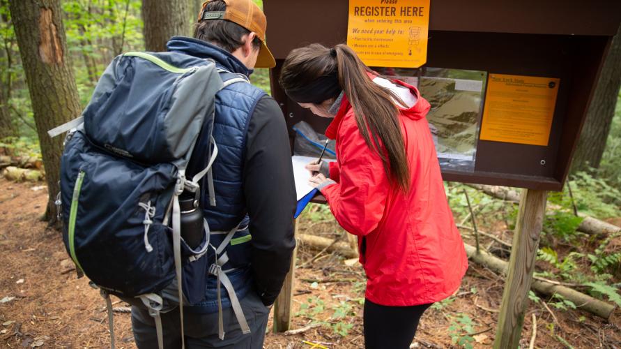 Two hikers sign in at an Adirondack trailhead