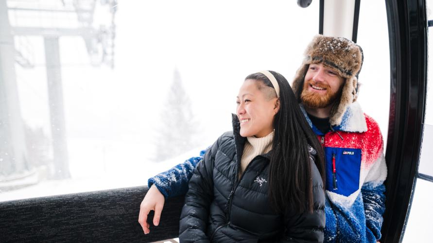 Two people step onto a gondola in the winter.