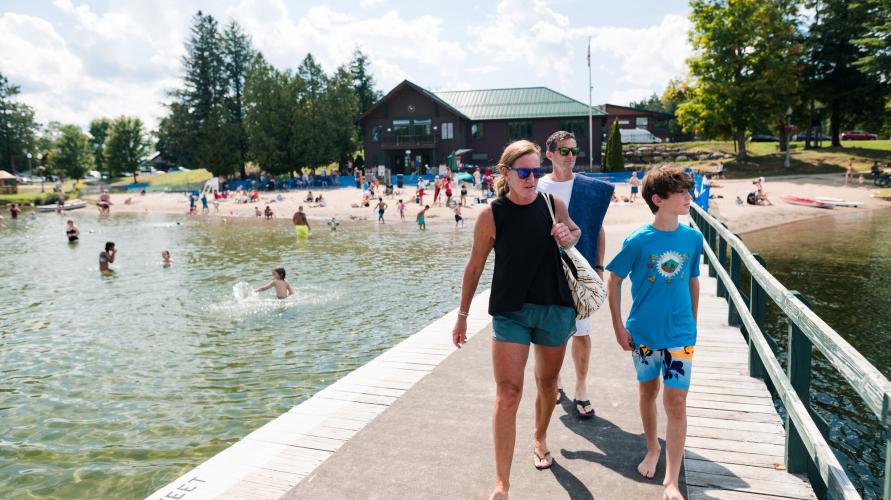 A family walks out on a dock at a swimming beach