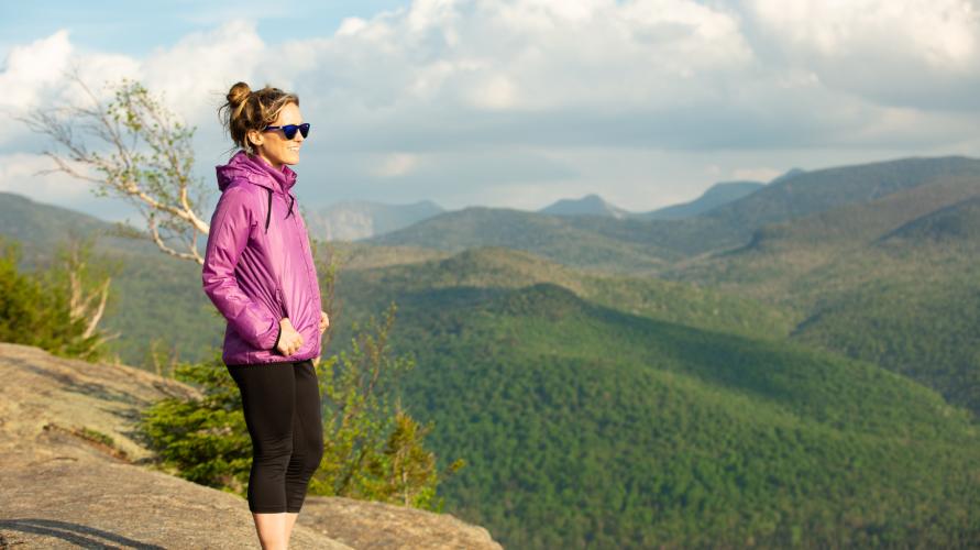 A woman on the summit of a mountain looks out over the Adirondacks