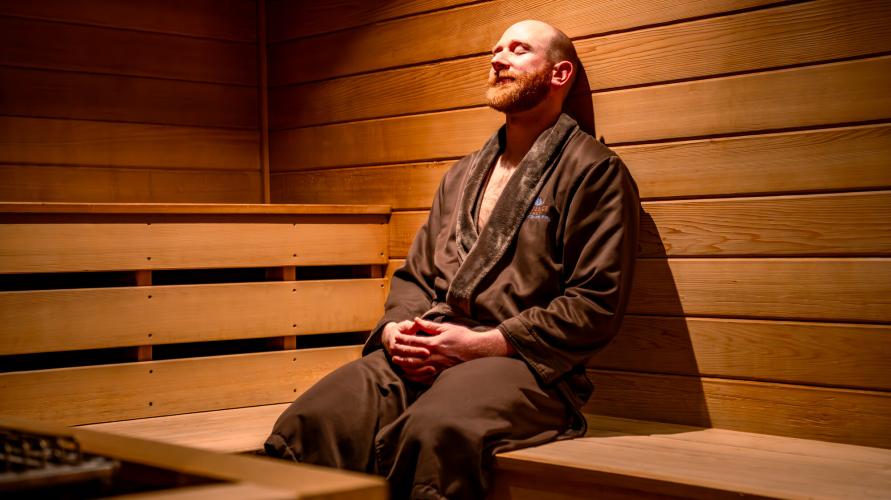 A man in a robe relaxes in a sauna