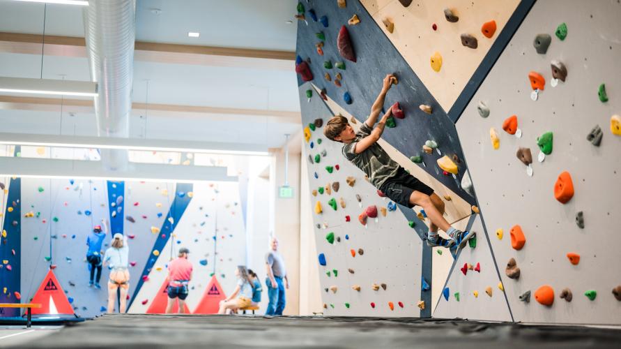 A boy climbs an indoor rock climbing gym