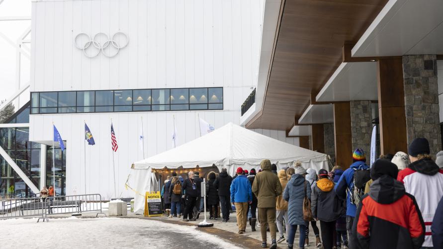 A line of people entering a tent outside of an event center.