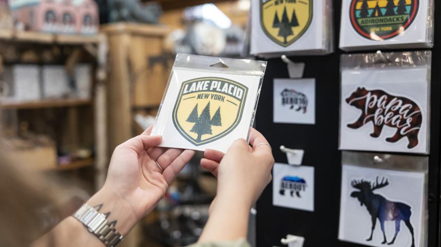 Hands holding Lake Placid sticker in gift shop