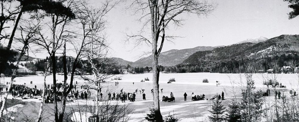 A vintage black and white image of people skating on a frozen lake.