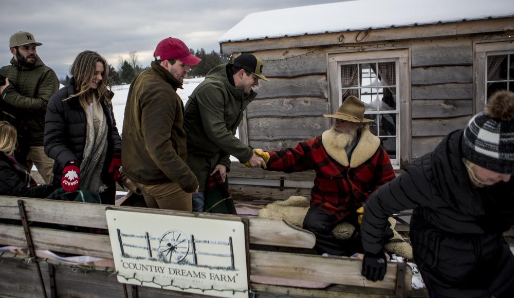 Group is welcomed onto the sleigh and shakes hands with the driver.