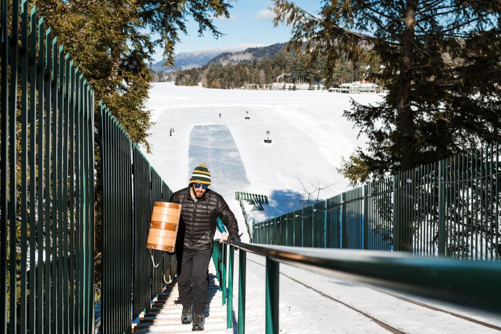 A man hauls a toboggan to the top of the Lake Placid toboggan chute.