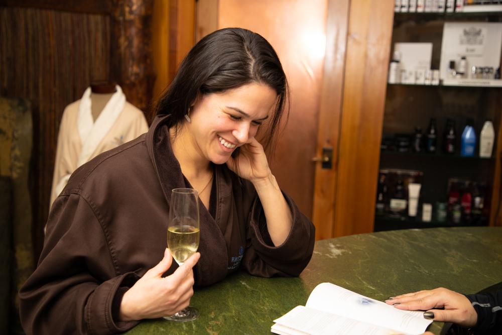 A women looks through the spa menu as she enjoys a glass of wine