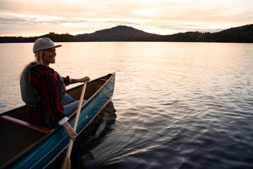 a woman paddles at dusk on the lake.