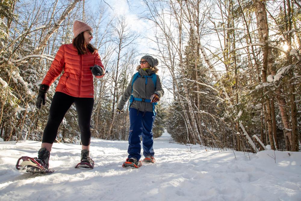 Two females chat as they snowshoe through the snow covered trees in Lake Placid